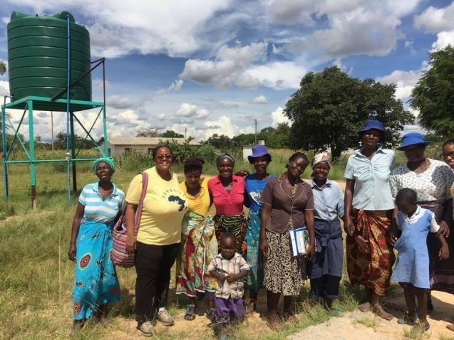 group of women standing in front of a water tank