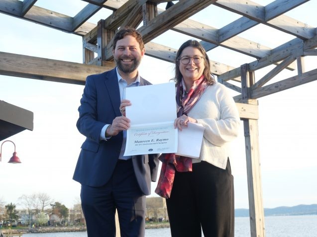 Maureen Raymo accepts a certificate of recognition from New York State Senator Elijah Reichlin-Melnick.