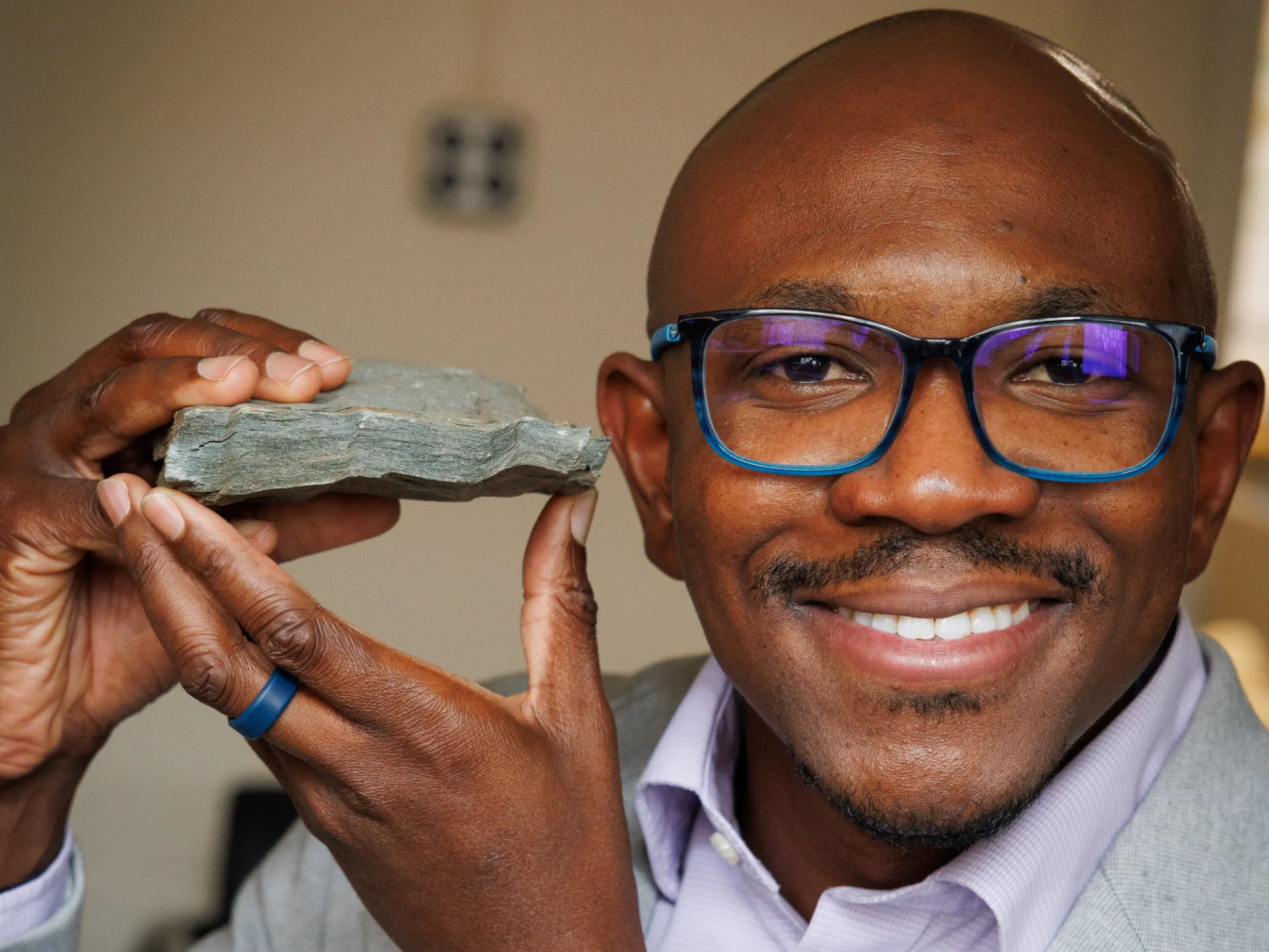Geologist Folarin Kolawole holding a rock with text 2026 Wayfinder Award Recipient.