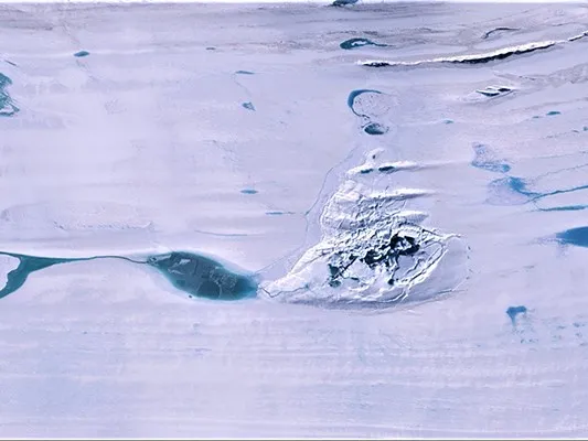 At center, the fractured ice of a doline on the Amery Ice Shelf, where a large subsurface lake drained through the bottom. Surface melt-water ponds surround the feature. Credit: NASA