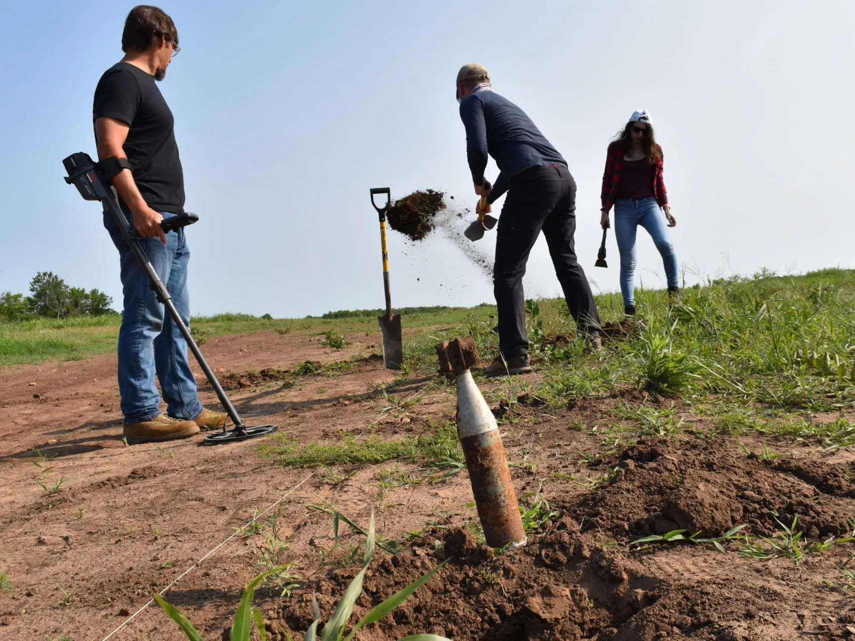 At an experimental explosives range in Oklahoma, a team searches for buried ordnance. Foreground, an unexploded U.S.-made M6A1 antitank rocket. Credit: Kevin Krajick