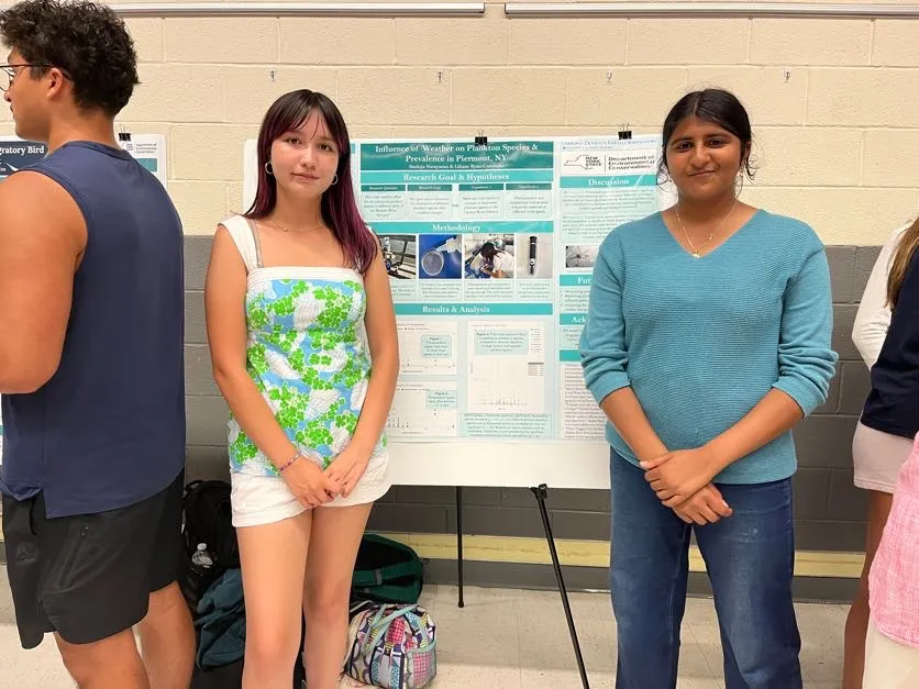 Next Gen interns Liliane and Sinduja standing in front of their research poster 