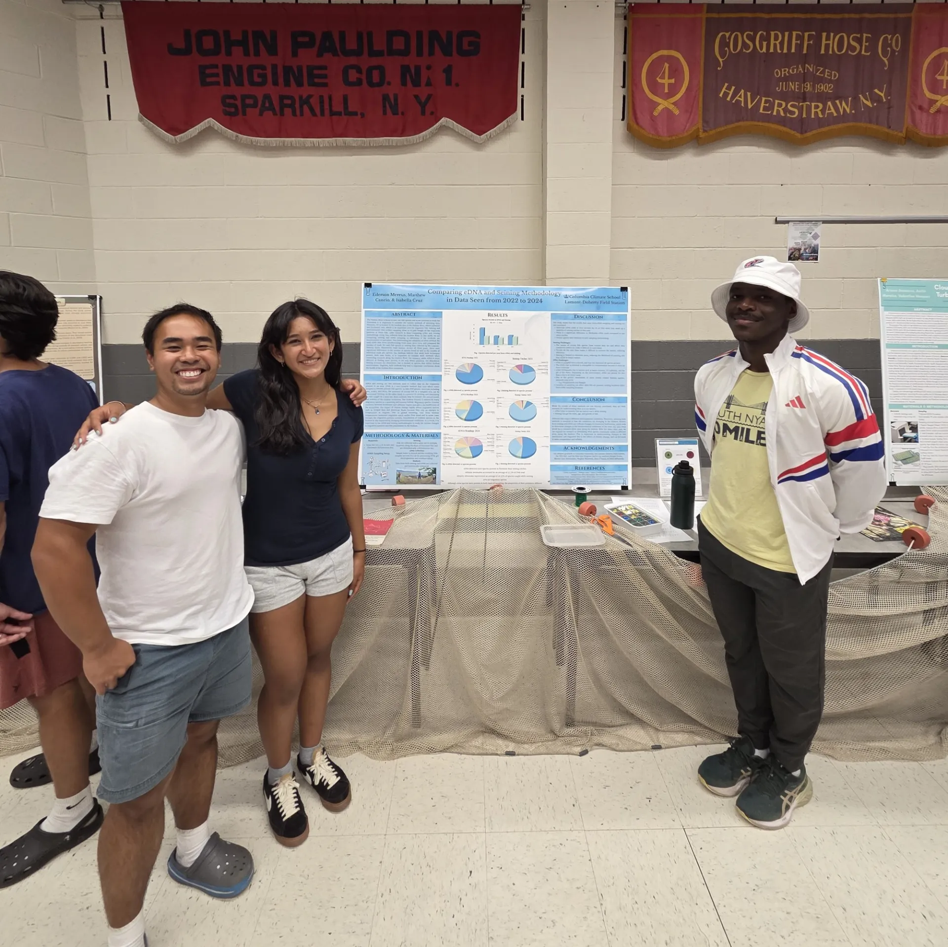 Next Gen Interns standing by research poster "Comparing eDNA and Seining Methodology.”