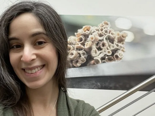 Logan Brenner in front of an image of corals