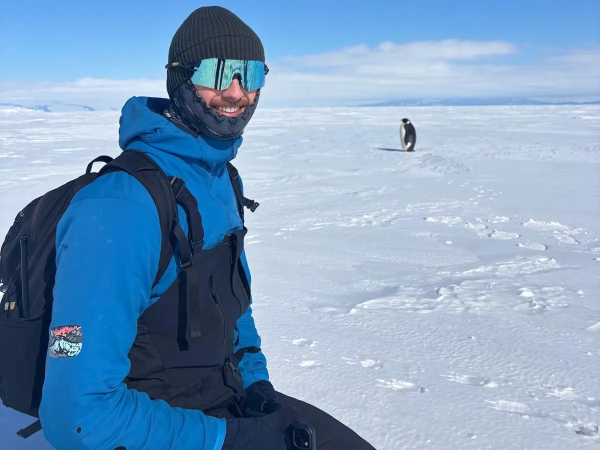 Sam Chester and an Emperor Penguin in Antarctica. Credit: SWASI2C