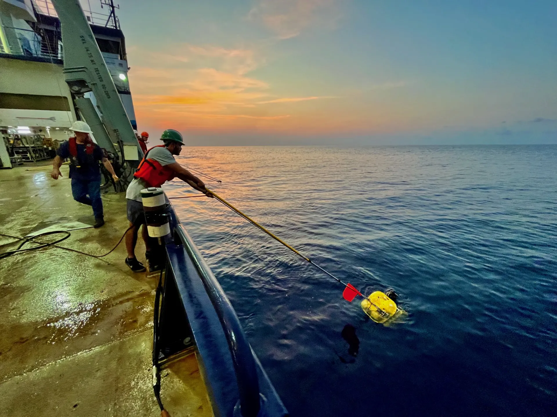 Hooking an ocean-bottom seismometer to bring back on board. Credit: Brandon Shuck