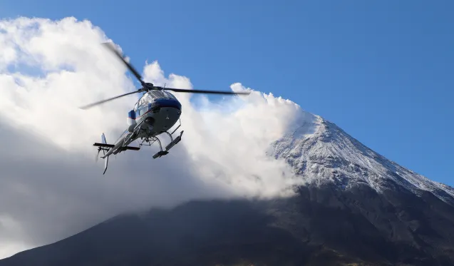 helicopter flying near steaming volcano