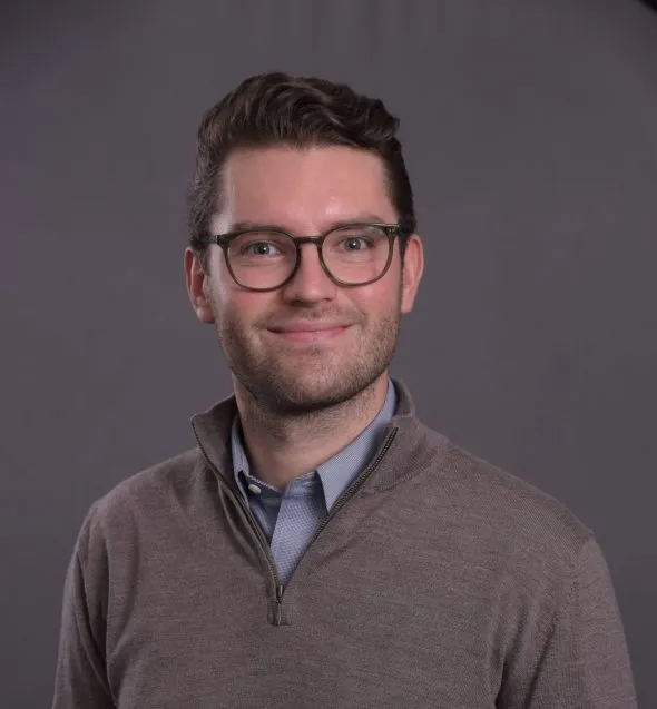 Man in glasses and sweater over collared shirt