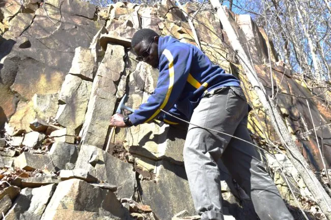 Man on cliff with hammer and chisel