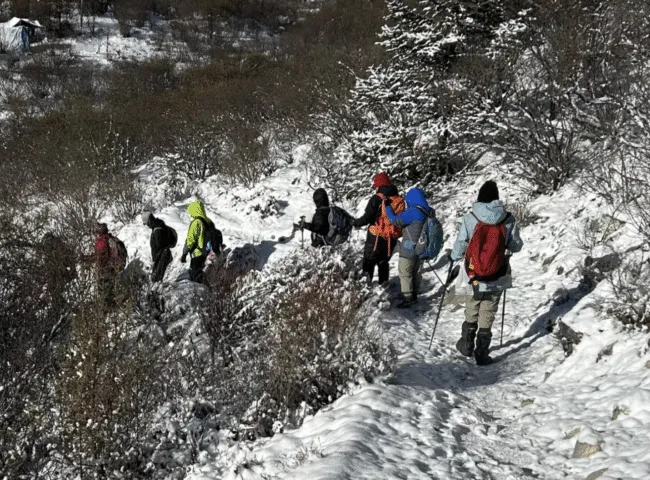 Women in jackets and bakpacks descend a snowy hike.