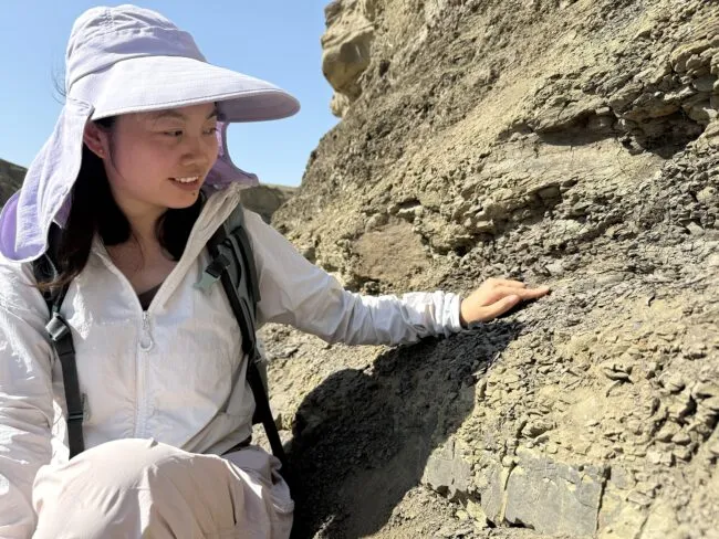 The study’s lead author, Yanan Fang, points to layer of volcanic ash in the sedimentary rock that shows evidence of ancient eruptions, dating back 180 million years. 