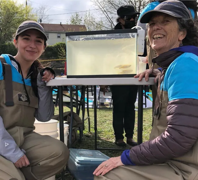 Two women pose near a fish tank
