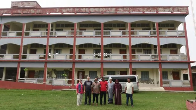 The research teams poses for a photo in front of a school