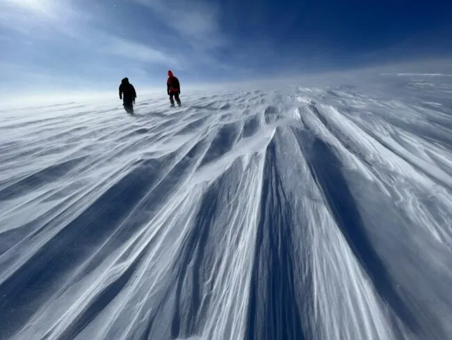 Two figures standing on a large sheet of ice—the Greenland ice sheet 