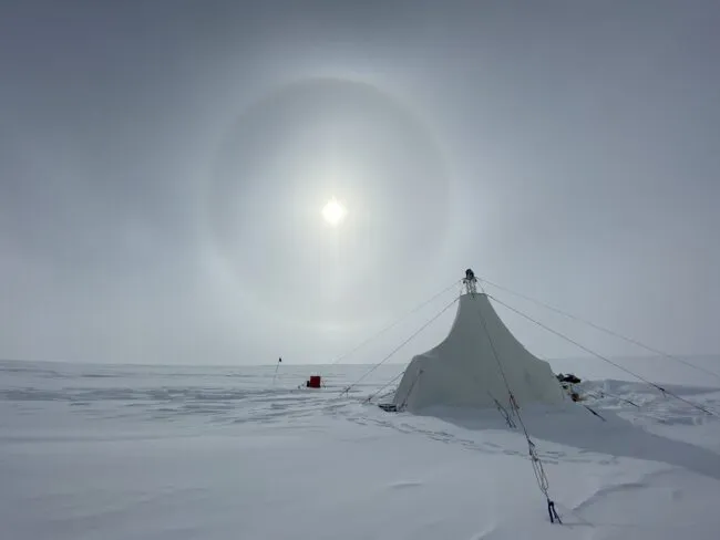 A white drill tent at the Allan Hills Blue Ice Area in East Antarctica, with a large sun halo