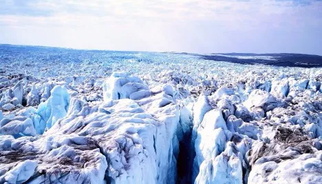 Glacier ice with deep crevasses stretching toward the horizon