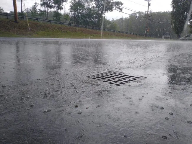 A stormdrain receiving water input during a high-precipitation storm in Massachusetts.