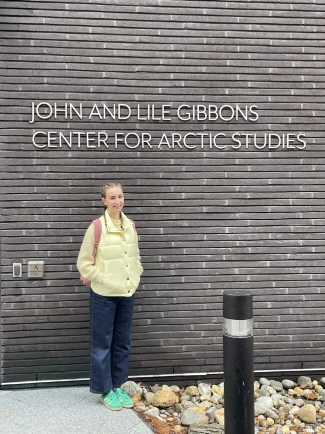 Person standing beneath a sign reading “John and Lile Gibbons Center for Arctic Studies.”