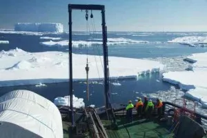 Sediment cores are lifted at the back of the boat.