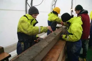 Geologists inspect a fresh sediment core.  Credit: Frank Nitsche.