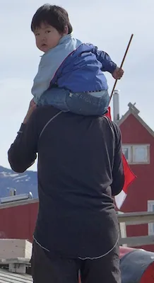 Community turns out to wait for helicopter.  Child is holding a Greenlandic flag. (Photo M. Turrin)