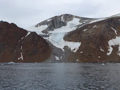 Magnus notes that the ice that drops down the red rock face of Kiatagssuaq remains year round. (Photo M. Turrin)
