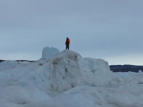 Gabriel Petersen climbs up to the top of the iceberg to check for open water. (Photo M. Turrin)