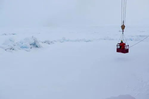 The 'man-basket' lowering Tim Kenna and crew member to the ice via crane to do sampling from a pressure ridge. (photo Bill Schmoker)