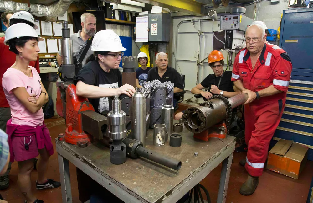 Bubba Attryde, a core technician, shows scientists on the <i>Joides Resolution</i> some of the ship's drilling tools. Tim Fulton/IODP