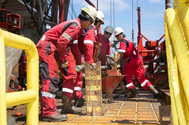 Professional rig personnel bring the first core aboard. Each segment is 9.5 meters long and is sectioned into smaller pieces for analysis and storage. (Tim Fulton)