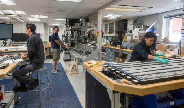 Sedimentologists Thibaut Caley of the University of Bordeaux and Andreas Koutsodendris of the University of Heidelberg and Deborah Tangunan, a paleontologist from the University of Bremen, work in the core lab aboard the JOIDES Resolution. Photo: Tim