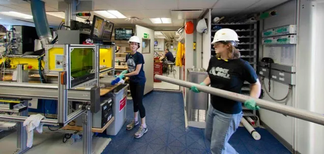 Alexis Armstrong and Beth Novak of the International Ocean Discovery Program (IODP) prepare a core for laser engraving aboard the <a href="http://joidesresolution.org/">JOIDES Resolution</a>. Photo: Tim Fulton/IODP