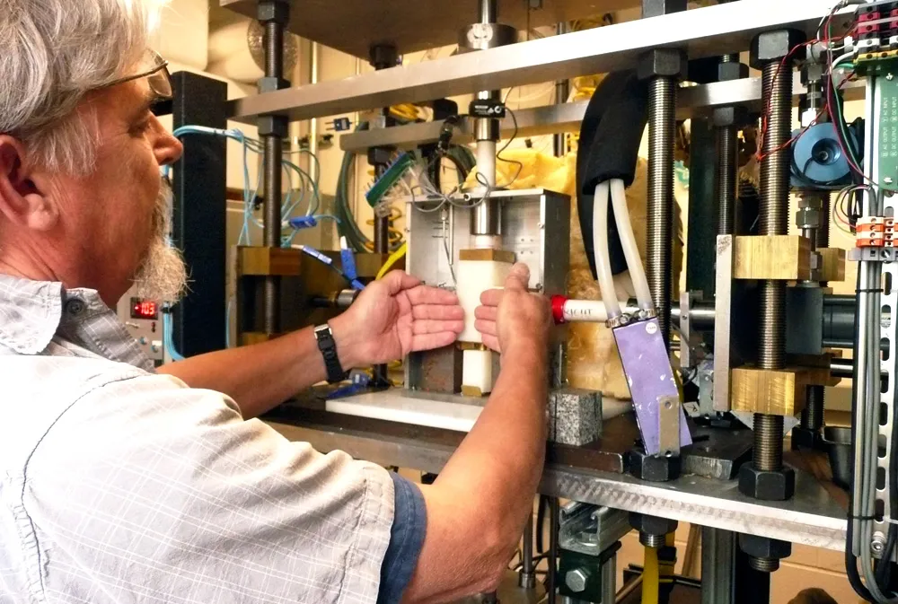 Research engineer Ted Koczynski explains how rock surfaces representing the rock bed of a glacier put pressure on a block of ice from each side as the ice is pushed downward in the new cryogenic deformation apparatus. Depending on the configuration, 