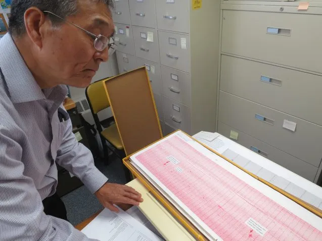 Seismologist Won-Young Kim pulls out the original paper seismogram showing the jet impacts, and subsequent collapses, of the World Trade Center towers. "It was a very painful day," he said. (Kevin Krajick)