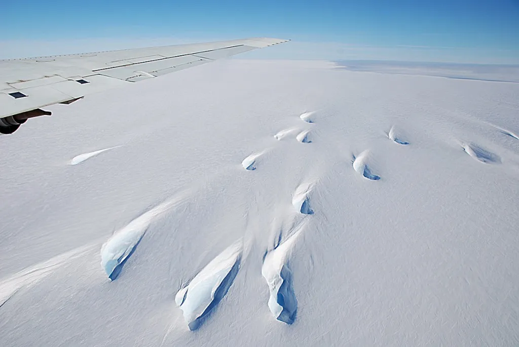 Snow-covered crevasses near the edge of Pine Island Glacier. Small meltwater ponds are visible even though it's early in the Antarctic summer.