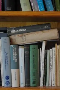 A shelf with many books about plants of different varieties.