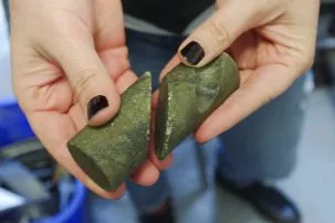 Heather's hands hold two cylindrical pieces of rock that have been cut on a diagonal to match up like puzzle pieces.