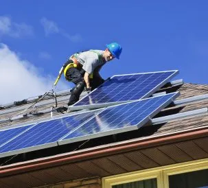man installing solar panels on roof
