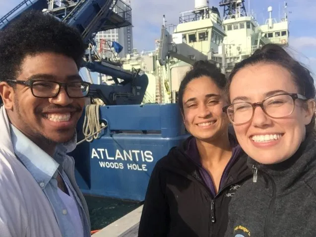 three students in front of a ship