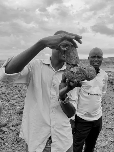 man holding up a fossil femur