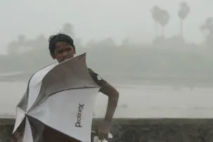 indian youth with umbrella in rain
