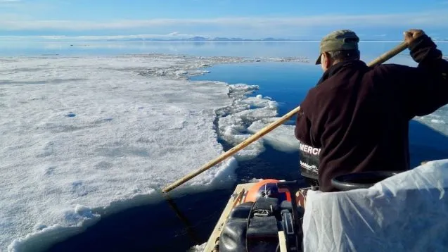 person in boat paddling through icy sea
