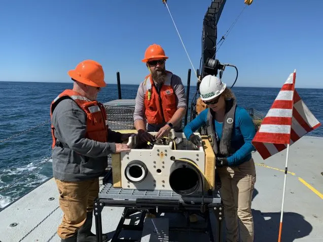 scientists in hardhats prepare large sensor